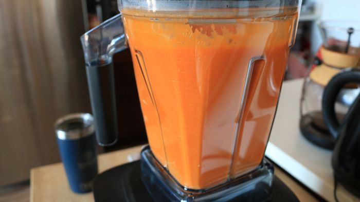 A blender now containing bright orange-red tomato soup.
