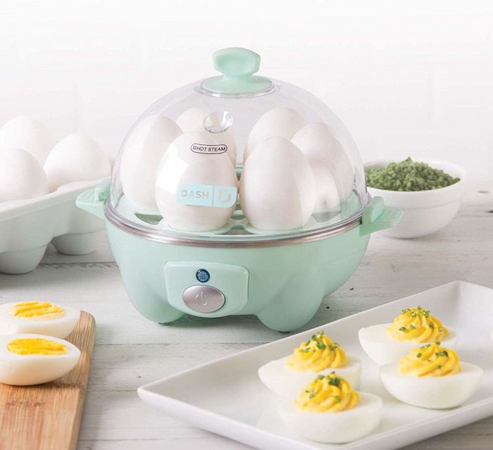 A mint-colored dome-shaped egg cooker with eggs cooking inside.