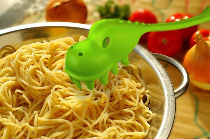A spoon that's green and shaped like a dinosaur, adding some fun to your kitchen!