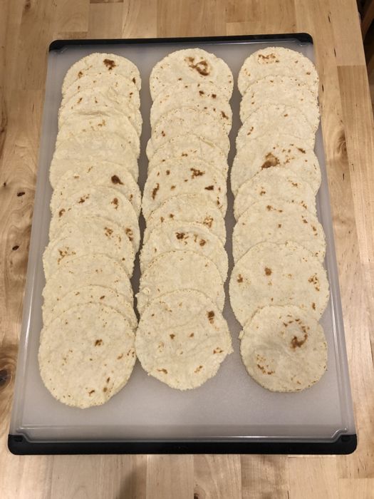 A cutting board loaded with freshly made tortillas, ready for use.