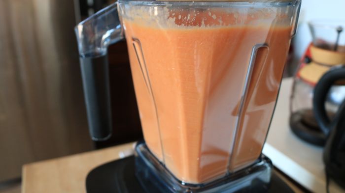 A blender filled with pale pink tomato soup.