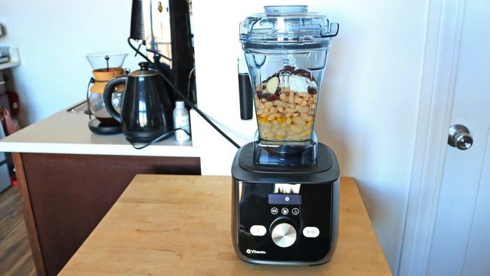 A Vitamix blender with a batch of beans inside its container.