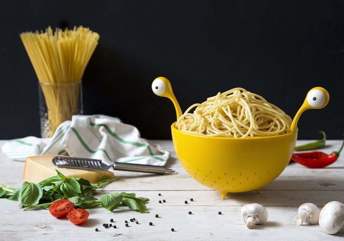 A yellow colander with monster eyes serving as handles, giving it a playful and quirky design.