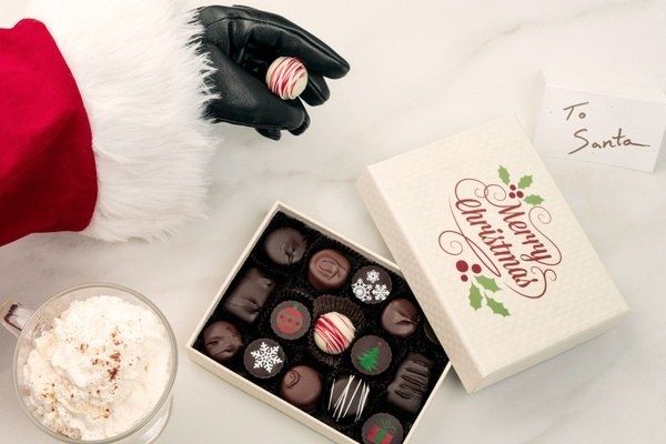 Santa's hand reaching into a box to take out a piece of chocolate.