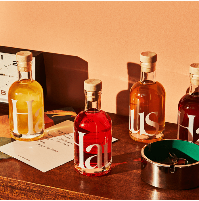 Four small transparent bottles filled with liquids in yellow, red, orange, and brown hues.