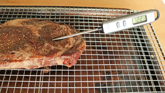 A thermometer reads 122°F in the center of the steak.