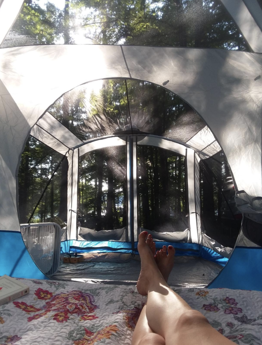 A reviewer taking a photo from the bedroom section of the tent, showing the expansive screened-in area and large awning