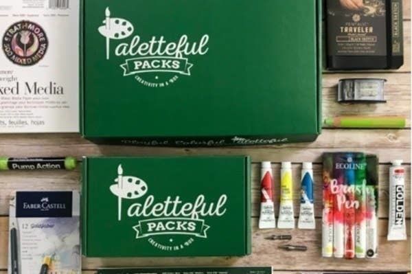 The exterior of the Paletteful Packs boxes along with supplies like paint and a mixed media book