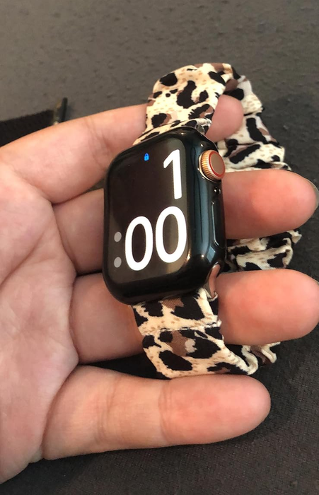 A close-up shot of a smartwatch adorned with a chic leopard print band, held in someone's hand, displaying the time as 1:00.