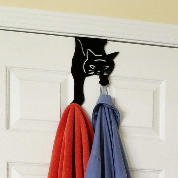 The cat hanger placed over a door, displaying a shirt and a towel