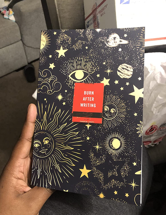 A reviewer holds up a journal adorned with celestial designs, the cover featuring mystical patterns.