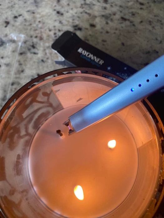 A reviewer using the rechargeable USB lighter to light a candle.