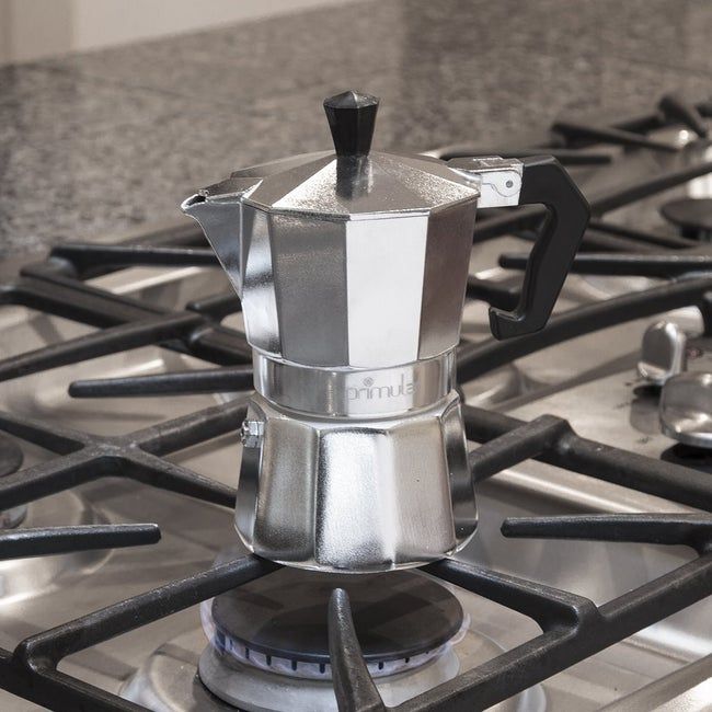 A silver espresso percolator resting on a gas stove.