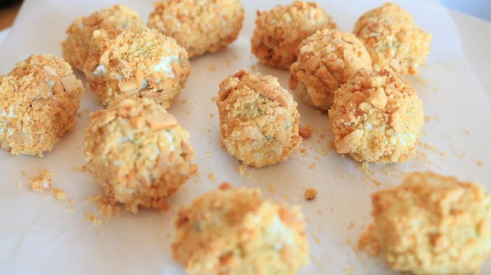 Grapes coated in cheese and ground nuts, arranged neatly on a plate.