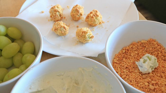 Bowls of grapes, a dip, and ground nuts are arranged beside each other, creating an appealing snack spread.