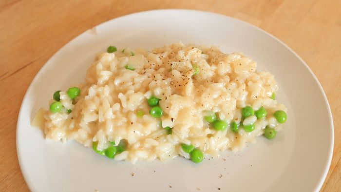 A single scoop of creamy risotto served on a pristine white plate.
