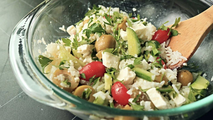 A fresh and vibrant rice and vegetable salad served in a bowl.