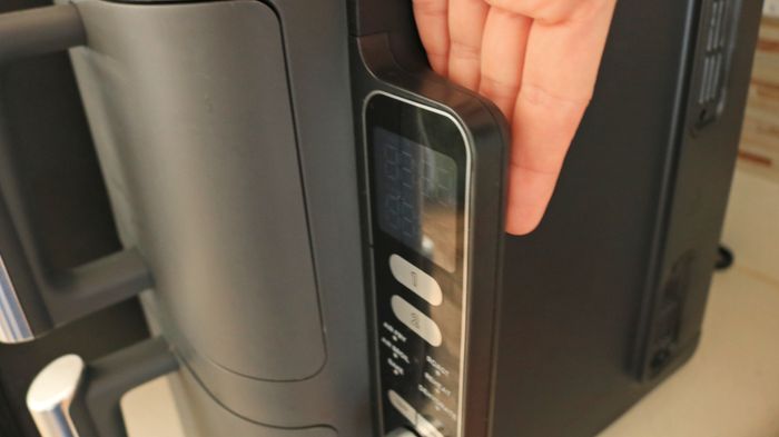 Hand resting behind the digital panel of the air fryer.