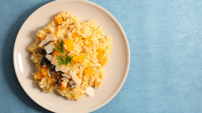 A plate of risotto topped with pumpkin and cheese chunks.