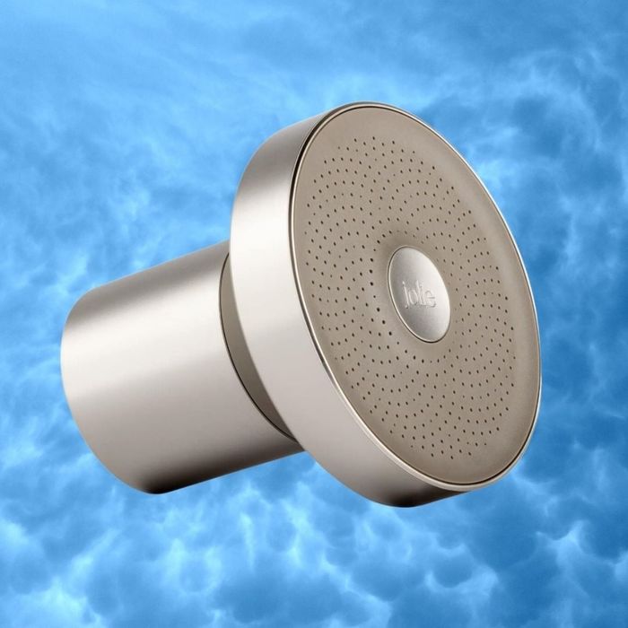 A contemporary showerhead with a sleek, minimalist design, set against a cloudy backdrop. The product bears the name 'Jolie.'