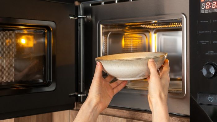 Someone is placing a bowl into a microwave.