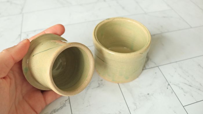 A hand gripping the lid of a butter bell.