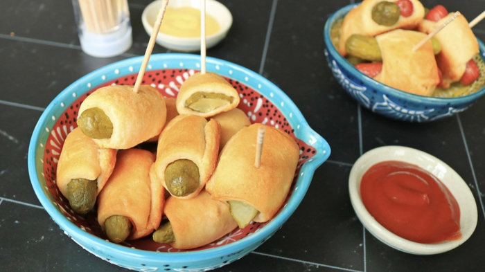Pickles wrapped in a blanket, served in a small bowl.