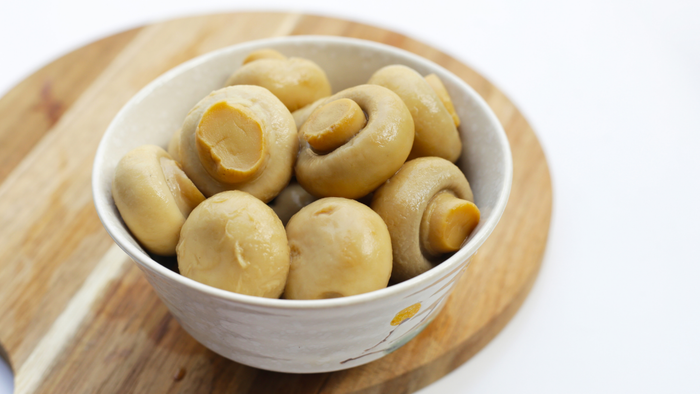 a small white bowl filled with canned mushrooms