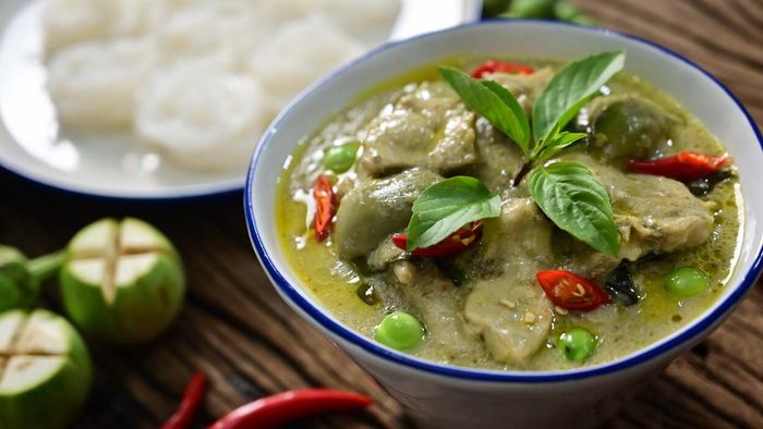A plate of vibrant green curry resting on a table.