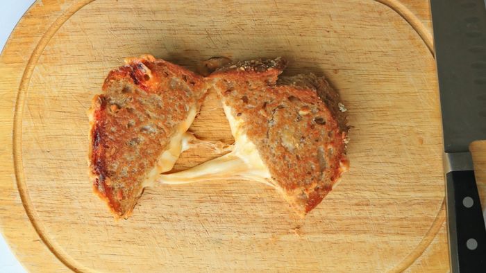A grilled cheese, sliced in half on a cutting board.
