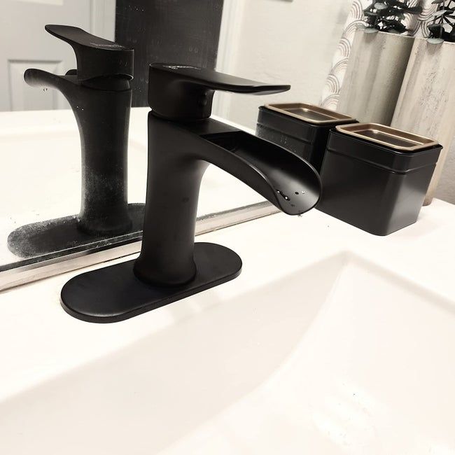A reviewer's photo of the black faucet installed in a tastefully decorated white sink area.