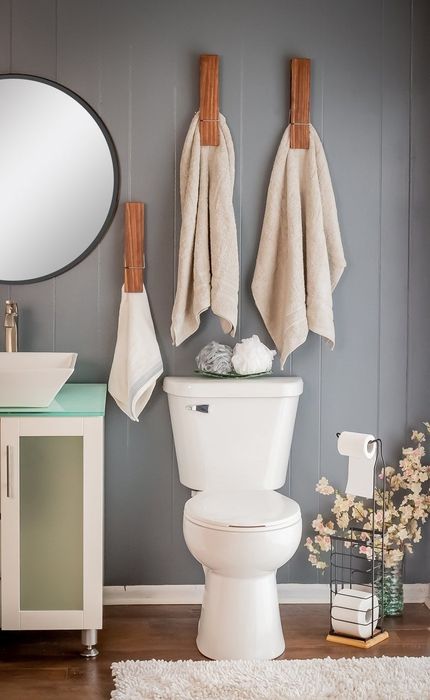 Three large clothespin-shaped towel holders mounted on the bathroom wall.