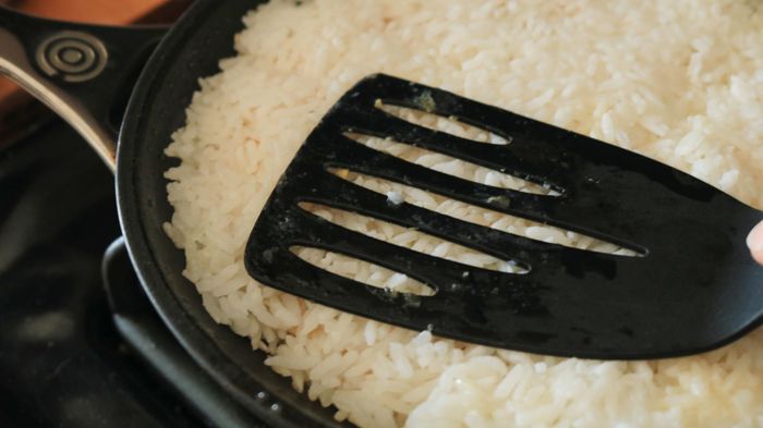 Spatula pressing rice into the frying pan.