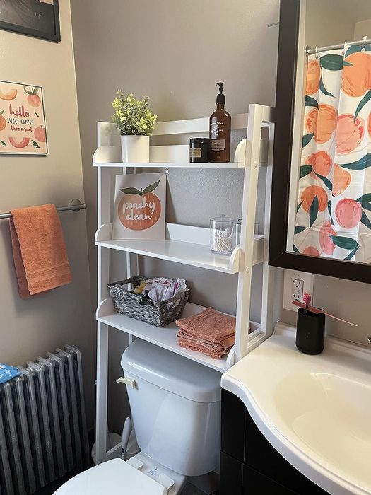 A reviewer's photo of the white version of the shelf, displaying toiletries and decorative knickknacks.