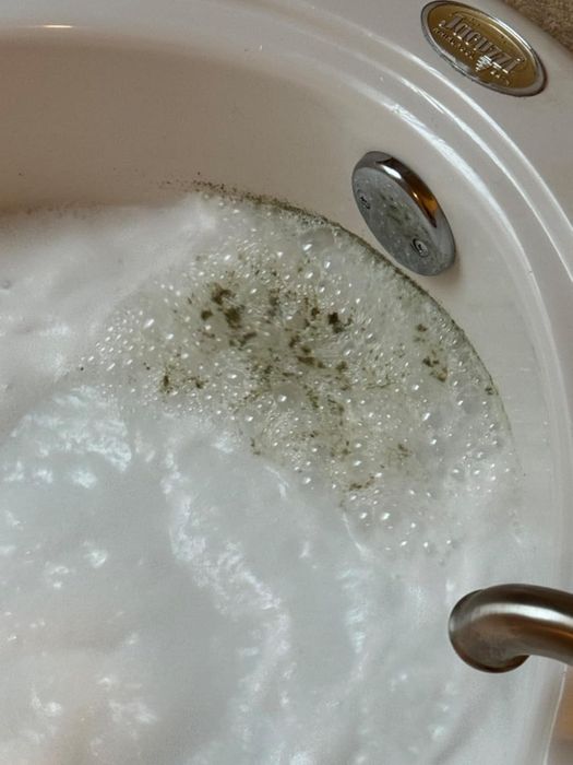 A bathtub with jets shows cloudy water and soap suds, emphasizing the need for a deep clean