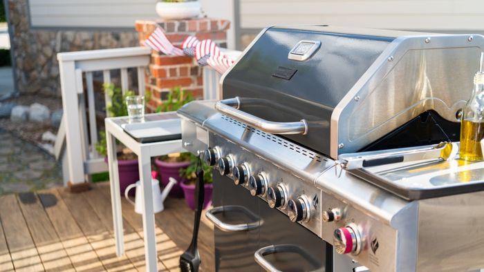 A gas grill placed on an outdoor patio.