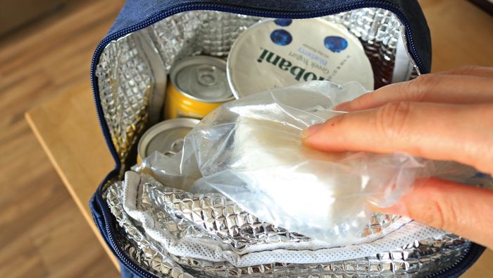A hand placing a cooler pack into a lunch box