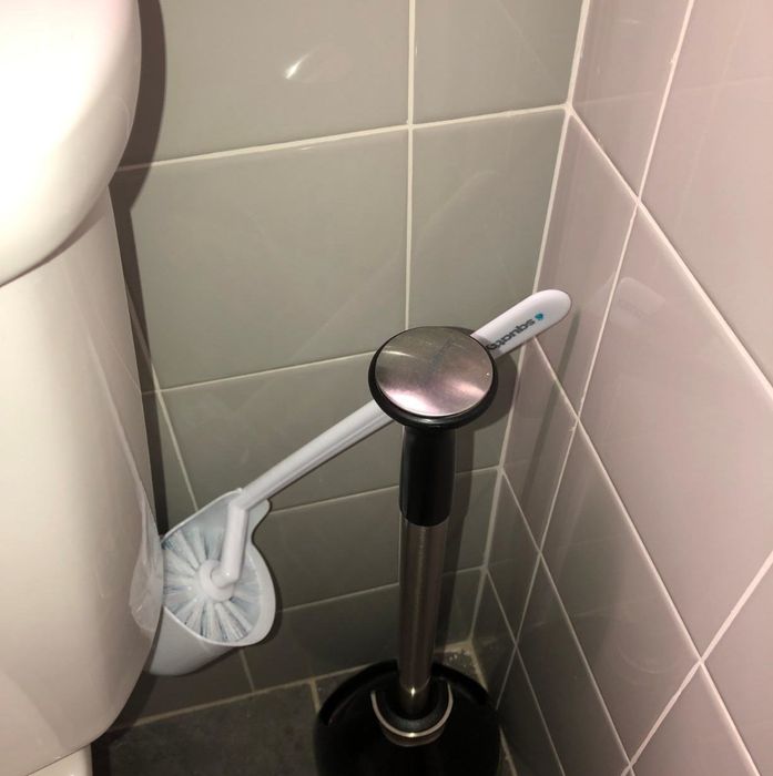 The toilet brush angled outward, ready to be grabbed for use.