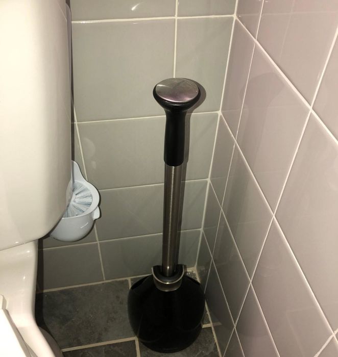 The toilet brush angled upward, barely visible for a tidy, inconspicuous look.