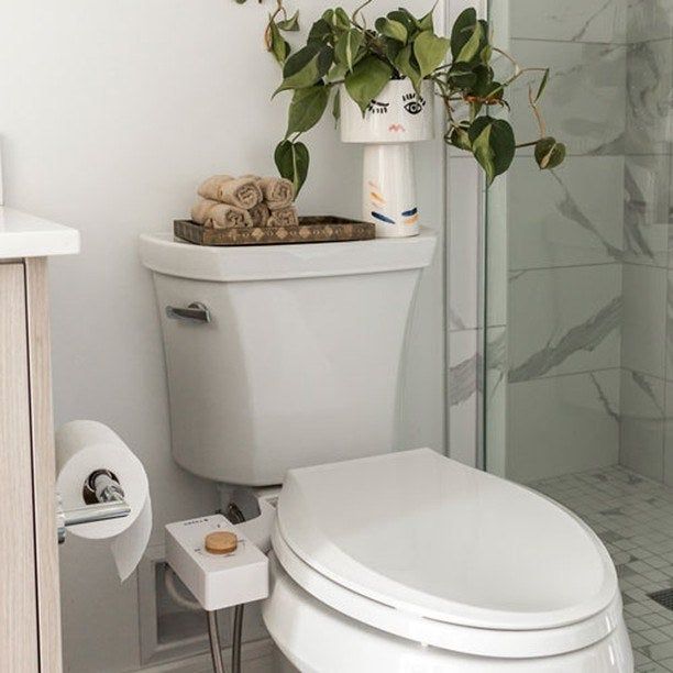 A white toilet seat with a matching white bidet and bamboo knob attached.