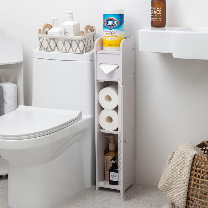 A bathroom storage unit neatly organizing cleaning supplies, toilet paper, and a basket of toiletries on a toilet tank.