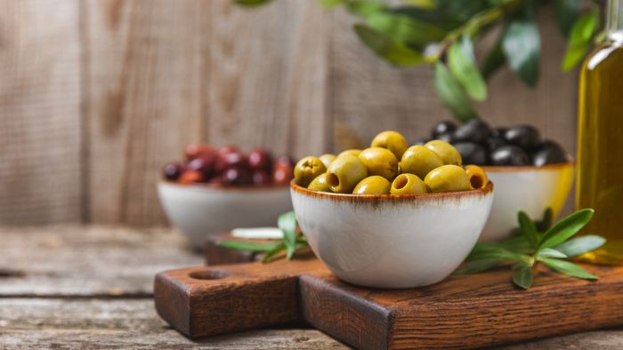 Three bowls filled with olives in various shades