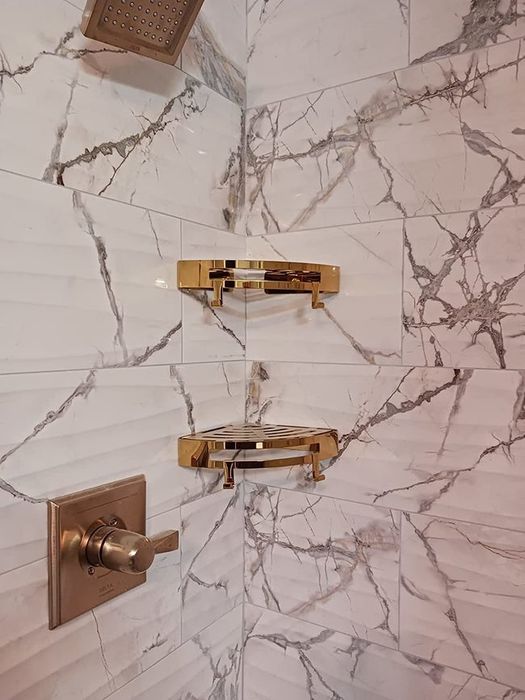 Reviewer photo showing gold shelves installed in a marble shower.