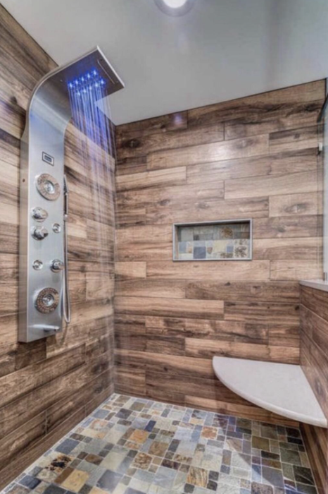 tiled shower with faux wood accents and a shower panel mounted to the wall