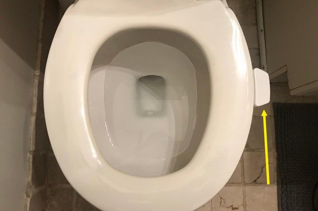 A white toilet seat lifter securely attached to a toilet seat.