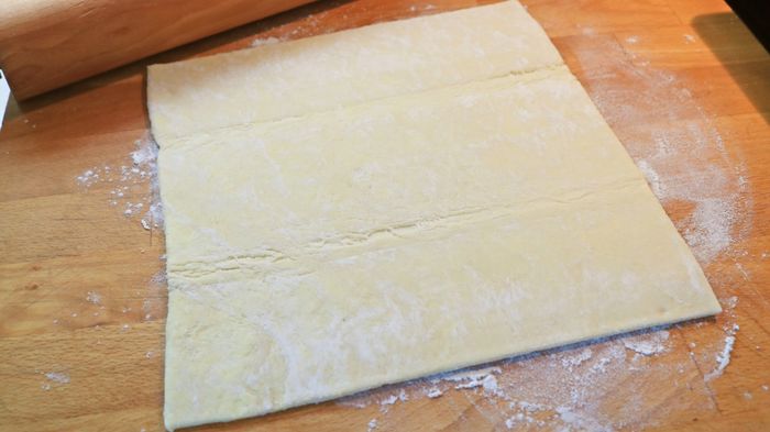 A sheet of puff pastry laid out on a cutting board.