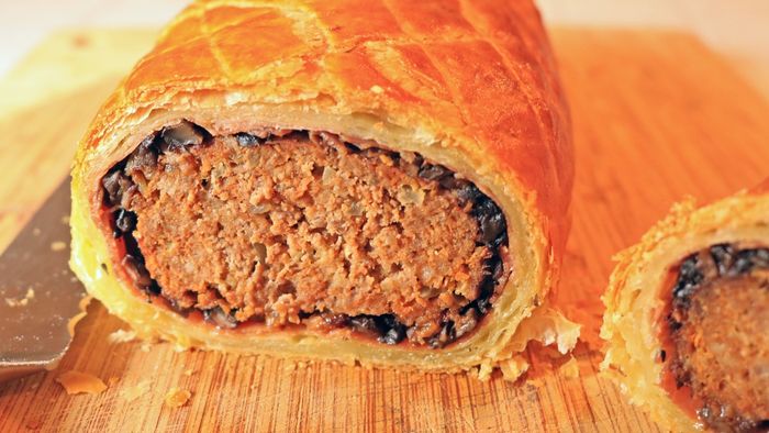 A slice of meatloaf Wellington placed on a cutting board.