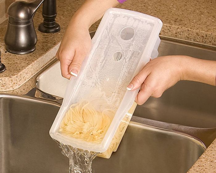A model draining water from a transparent rectangular cooker filled with pasta.