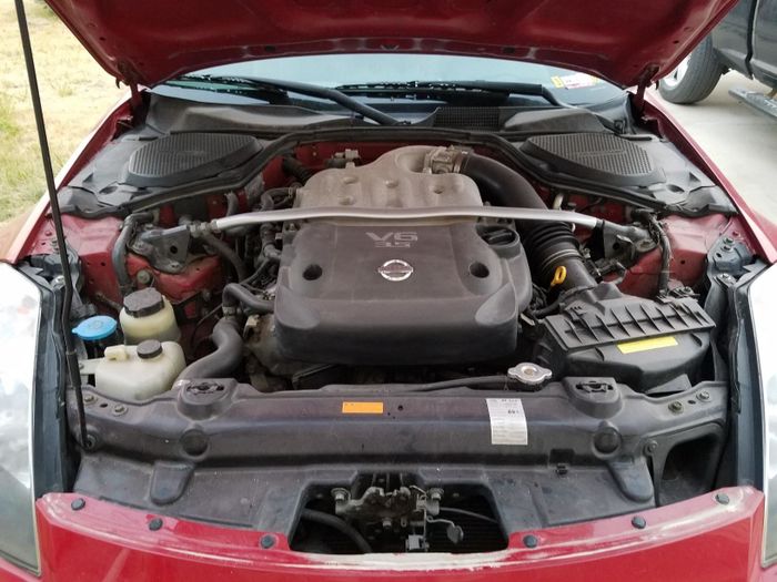 A photo showing a car’s hood open, revealing a dirty engine compartment