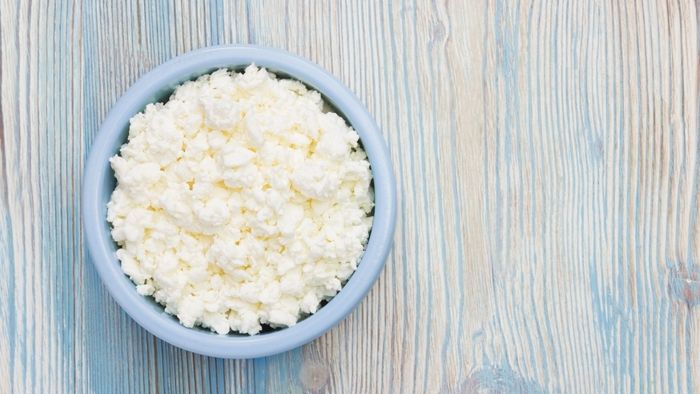 A bowl of cottage cheese resting on a wooden surface